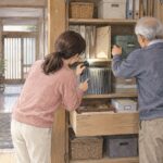 高齢の父と娘が実家の収納棚を開けて契約書や重要書類を探す水彩イラスト